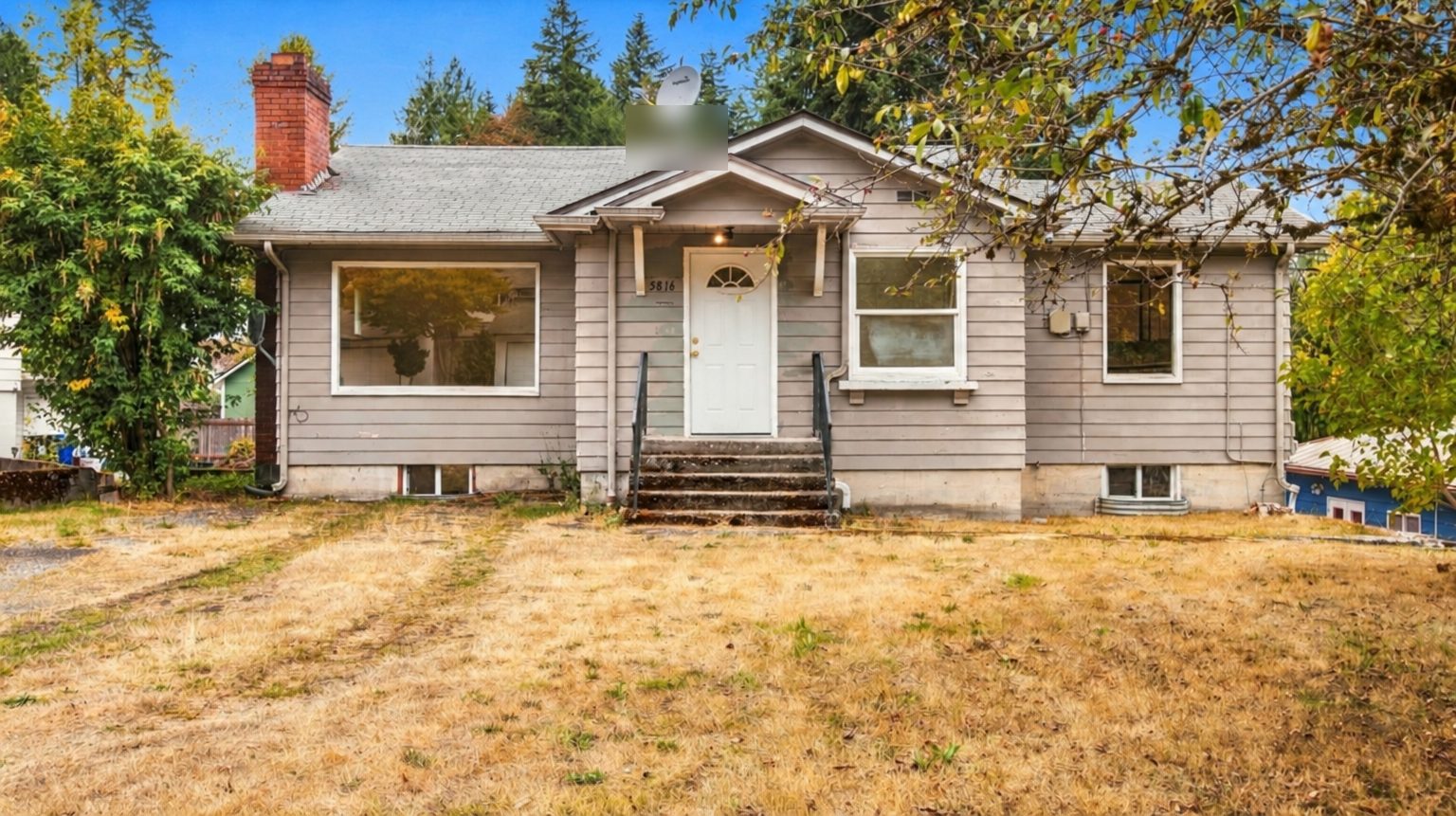 Older gray cottage with a dry front lawn, photographed as listed