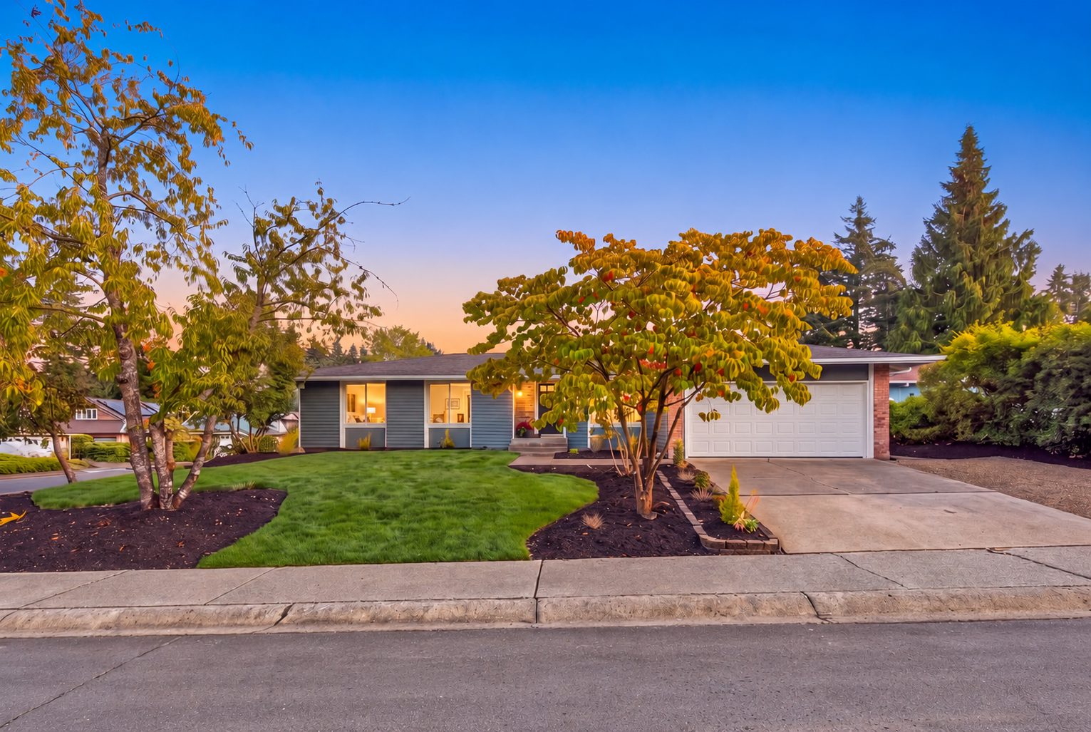 Blue single story home with fall trees in the front yard