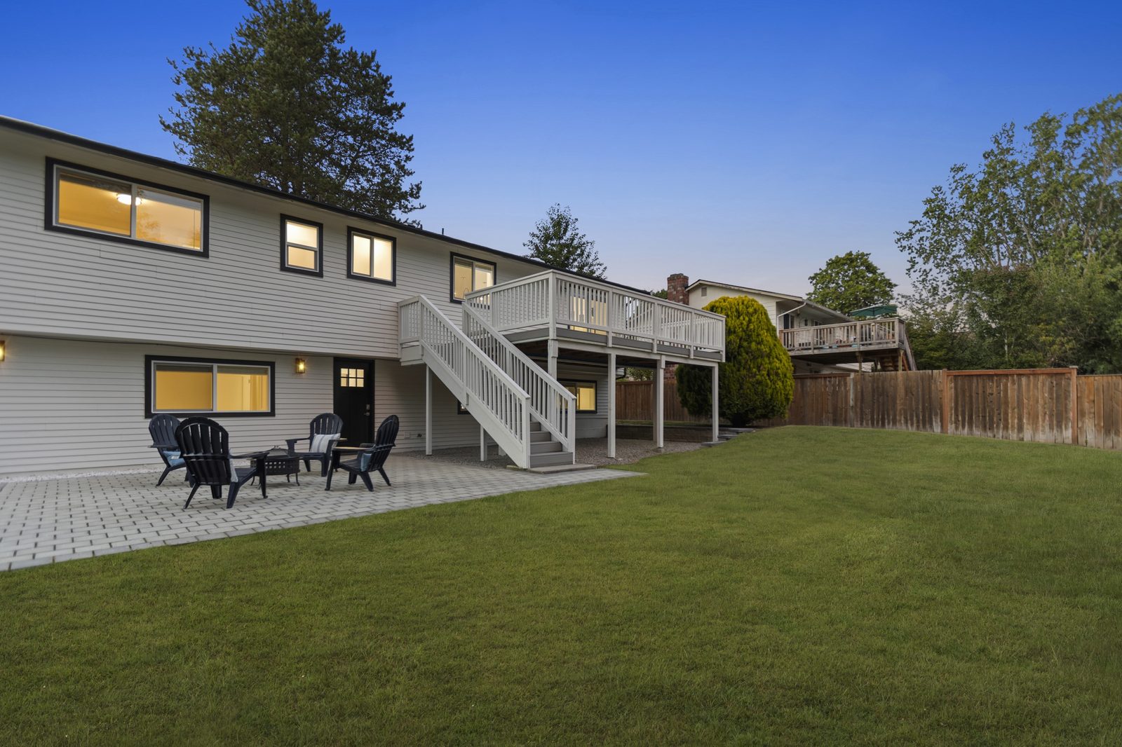 Large backyard lawn with a patio and a raised deck
